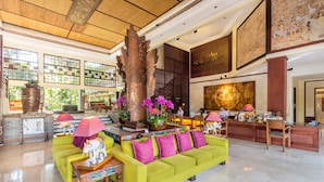 A spacious lobby with a bright yellow sofa, a large wooden sculpture, and a reception desk. - Risata Bali Resort and Spa (Kuta)