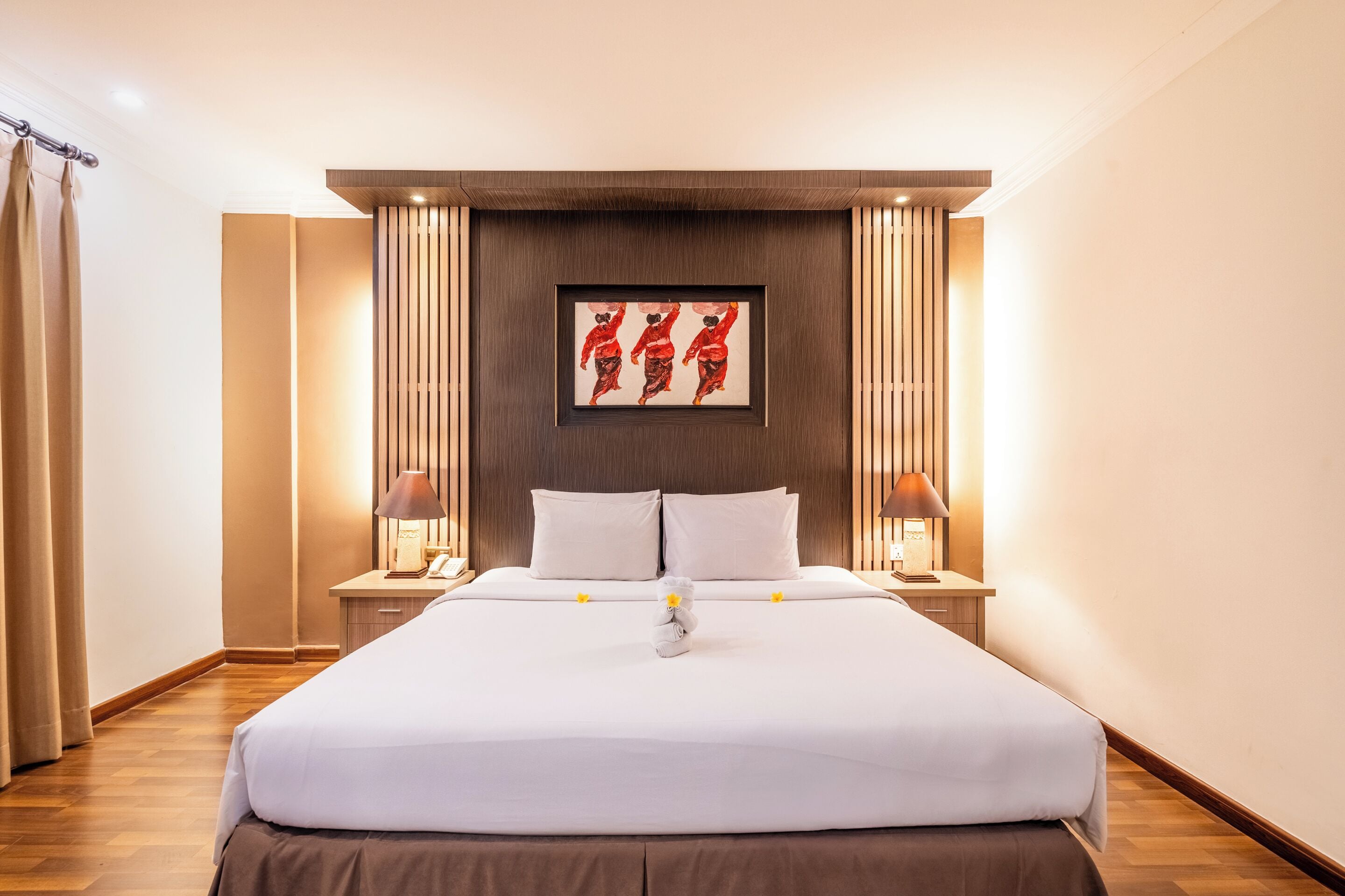 A neatly made bed with white linens, two bedside tables with lamps, and a framed artwork above the bed.