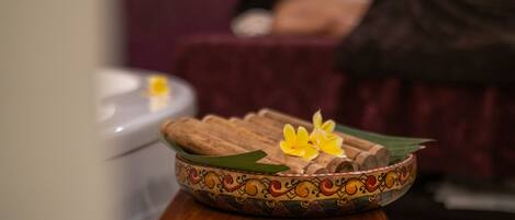 A wooden bowl with decorative patterns and flowers on a wooden table.