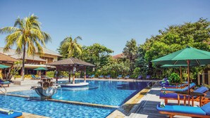 A pool area with lounge chairs, umbrellas, and a water feature. - Risata Bali Resort and Spa (Kuta)