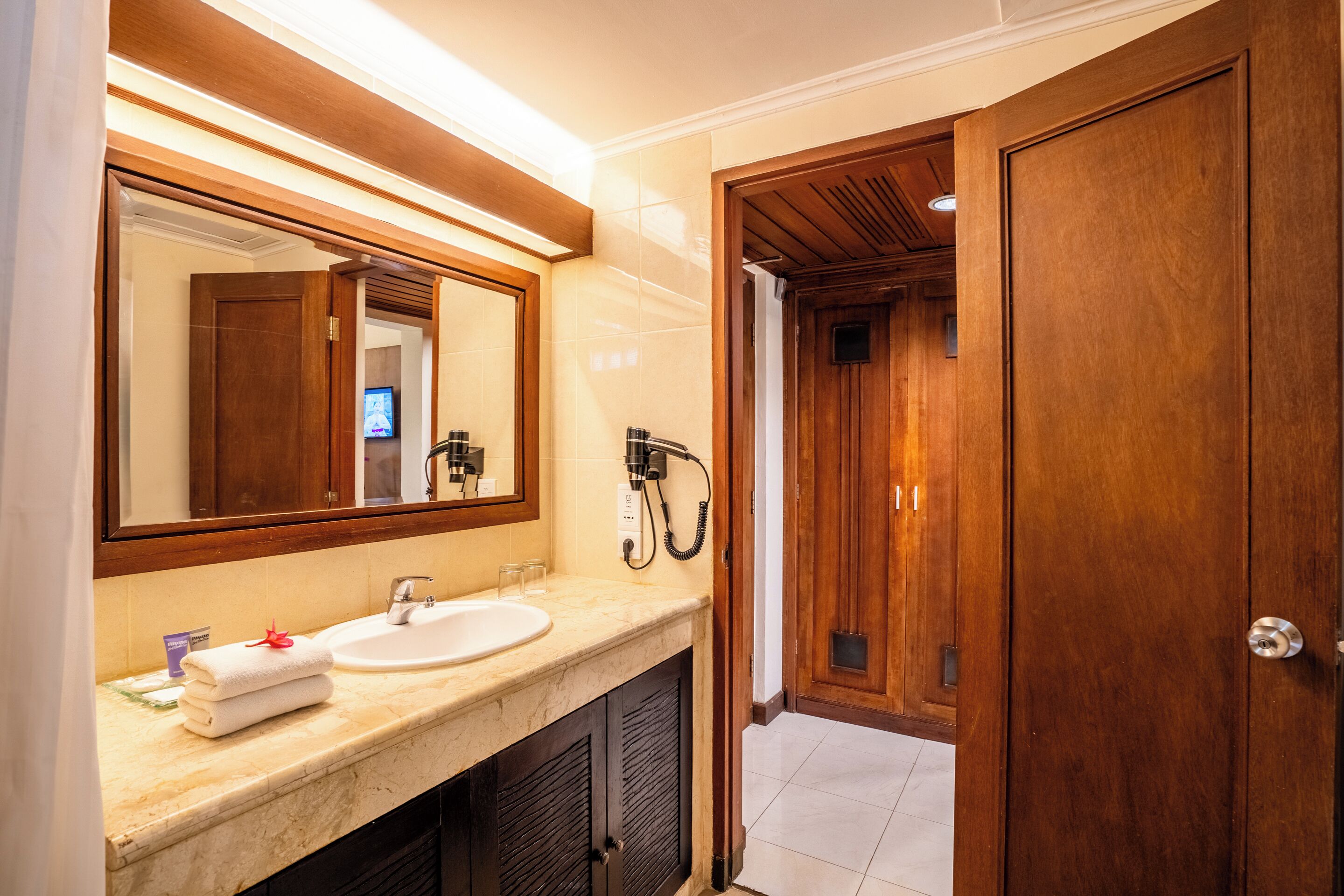 A bathroom with a large mirror, a sink, and a shower area.