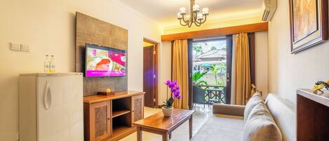 A living room with a sofa, a TV, a small table, and a refrigerator.
