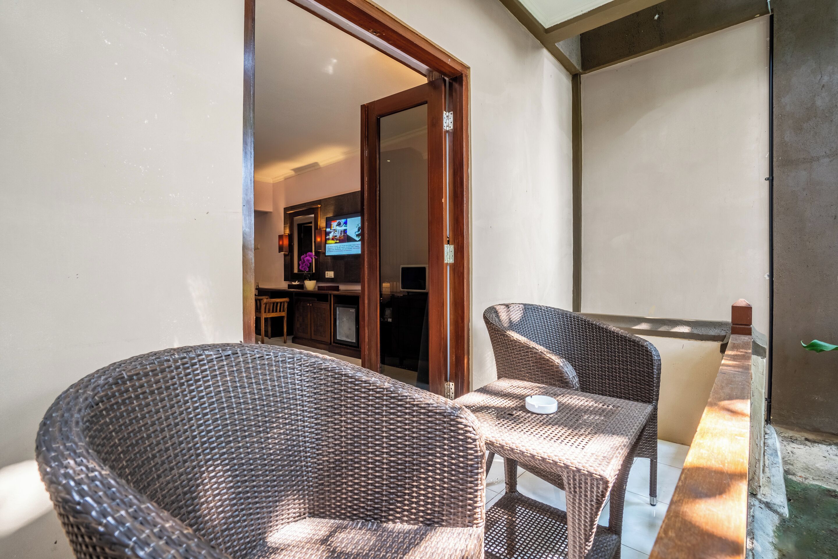 A balcony with wicker furniture and a television in the background.