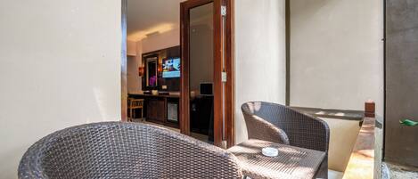 A balcony with wicker furniture and a television in the background.
