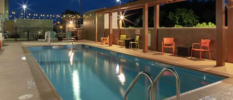 Piscina com pergolado, cadeiras e placa indicando profundidade de 1,5 metros.