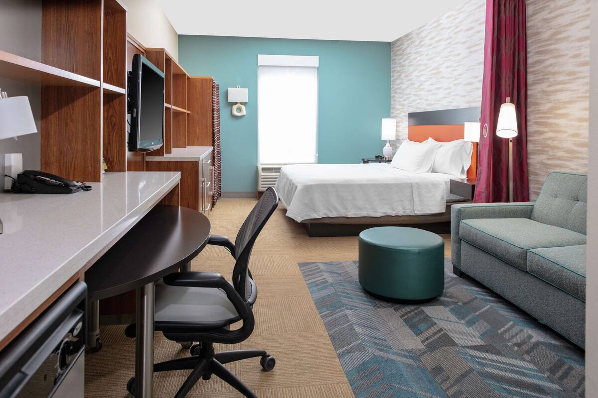 Ein Hotelzimmer mit Schreibtisch, Stuhl, Bett und einer Couch.