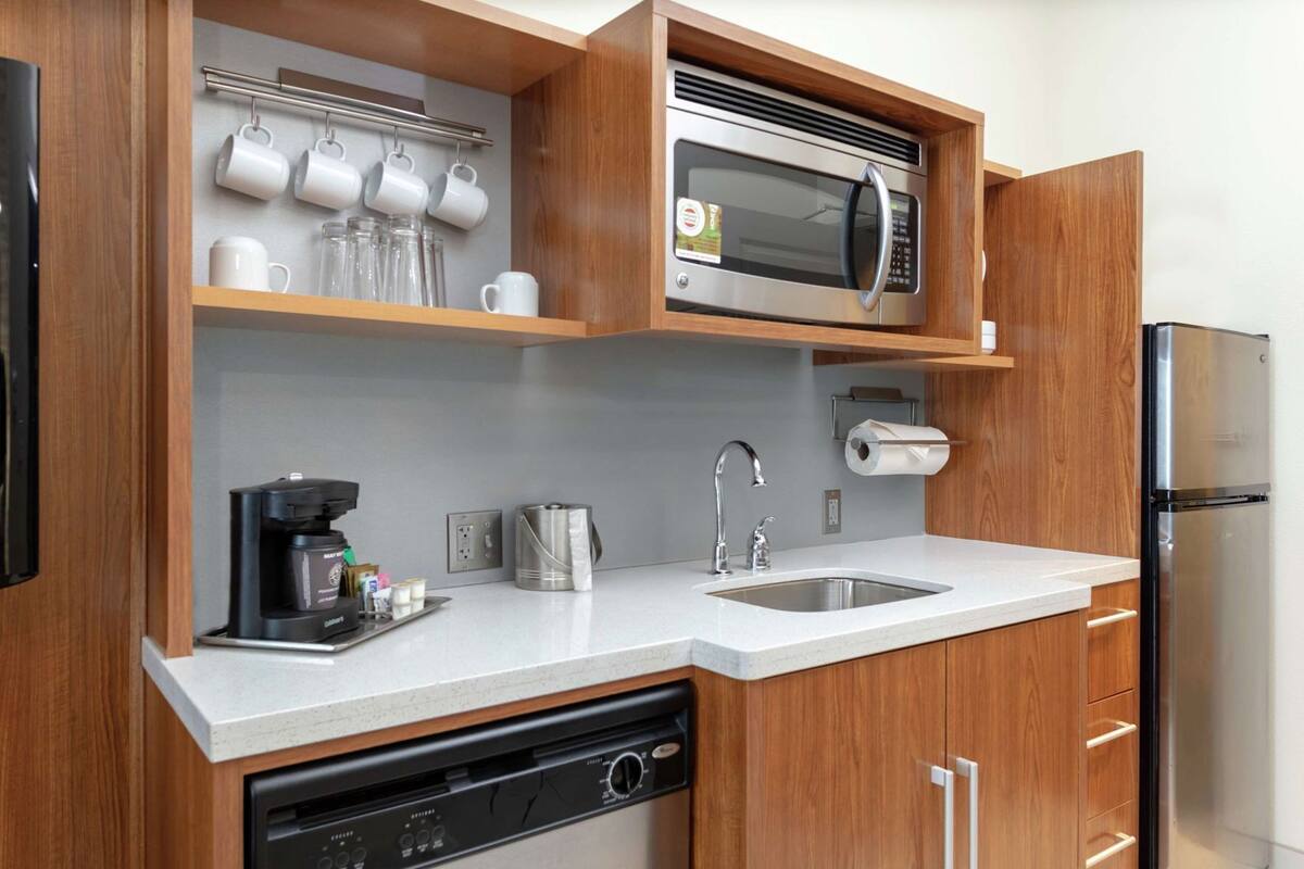 Une cuisine compacte équipée d’un four à micro-ondes, d’une machine à café, d’un lave-vaisselle et d’un réfrigérateur.