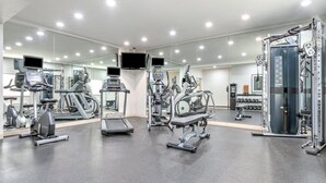 Een moderne sportschool met diverse fitnessapparaten, waaronder loopbanden, elliptische trainers en krachttrainingsmachines.