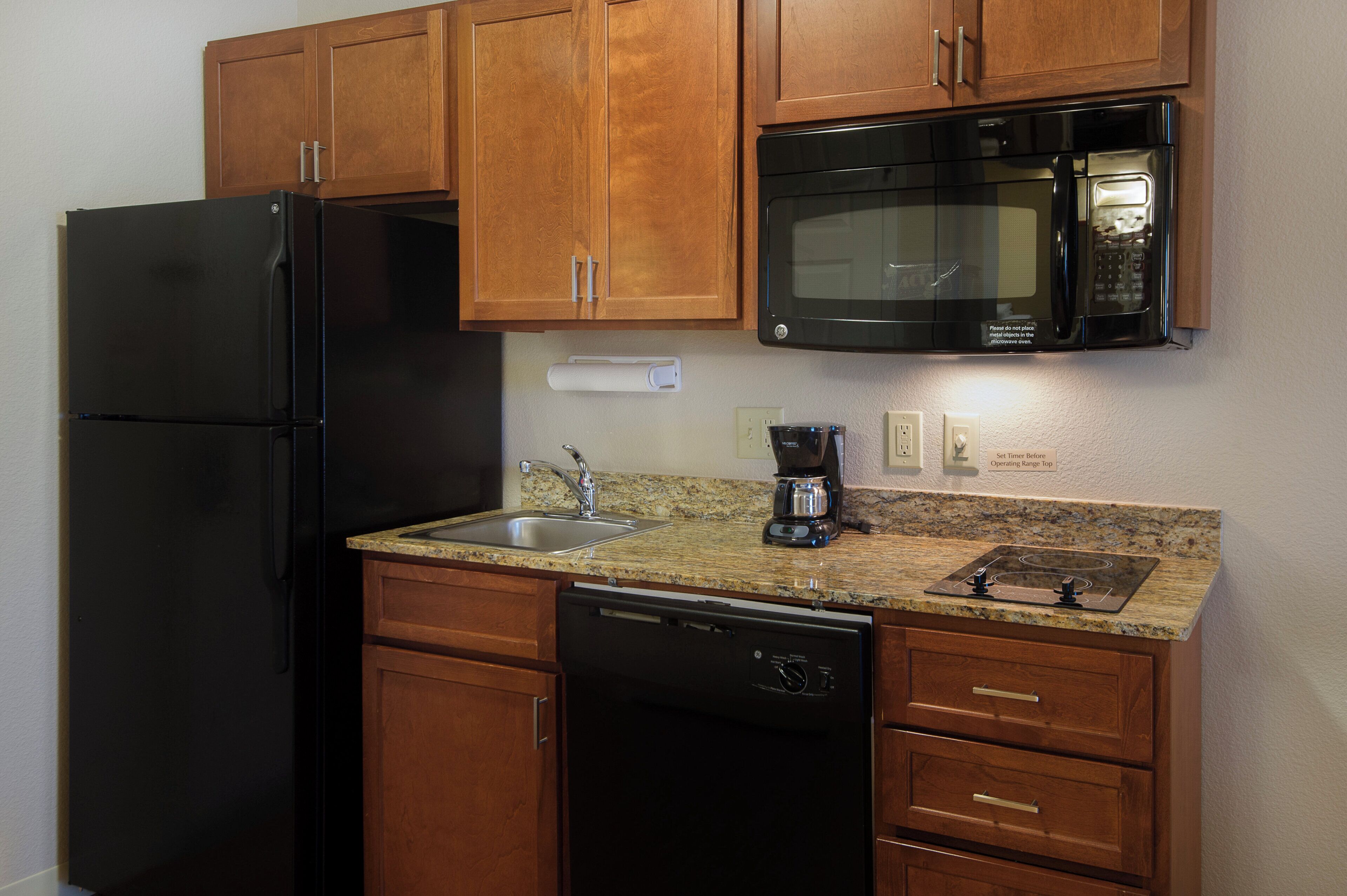 A compact kitchen with a refrigerator, microwave, coffee maker, and dishwasher.