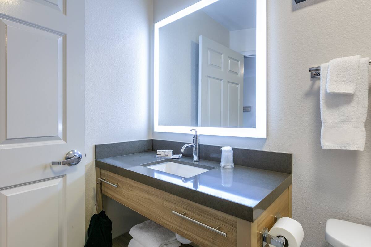 Een badkamer met een wastafel, spiegel, handdoekhouder en toilet.