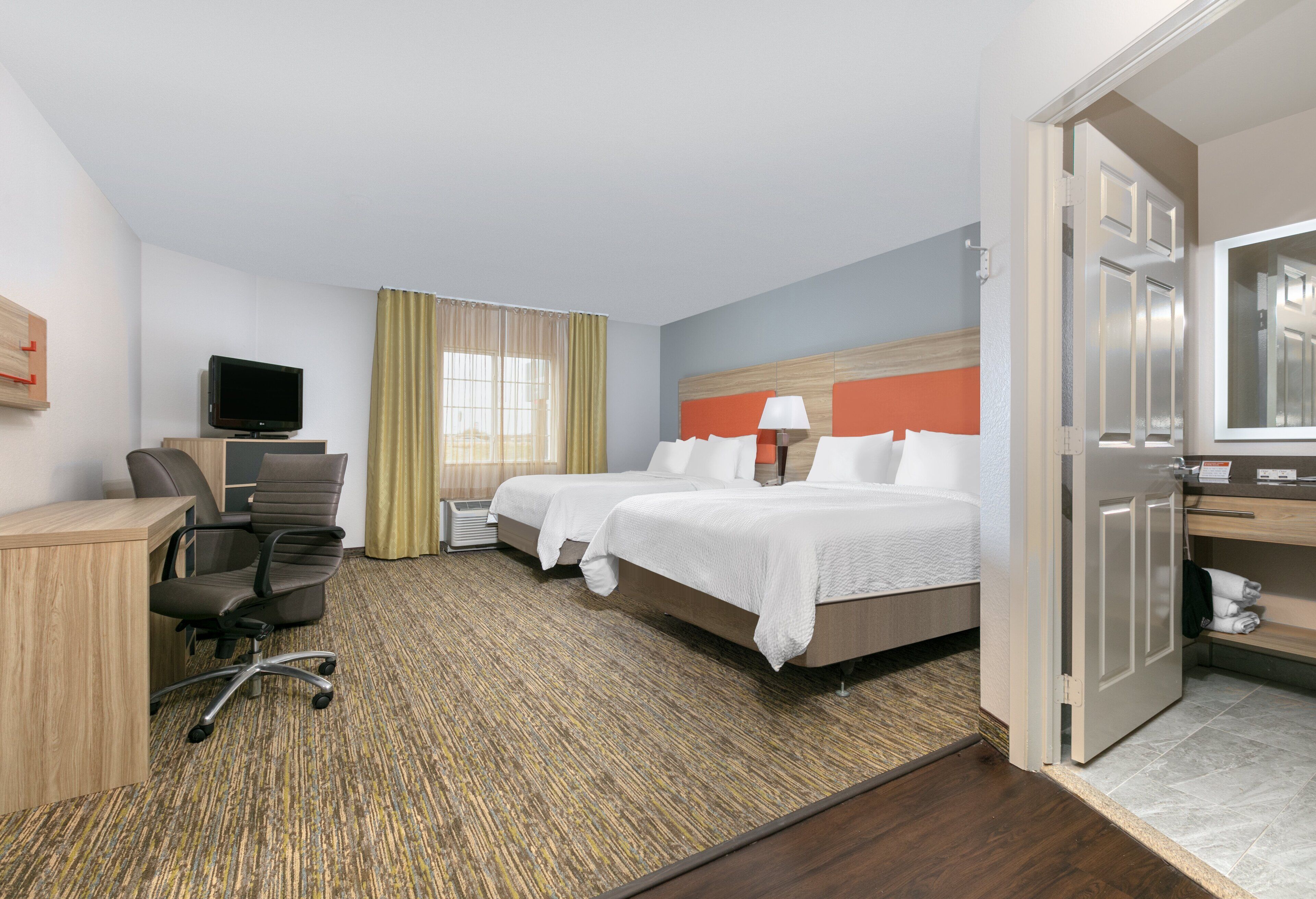 Une chambre d’hôtel avec deux lits, un bureau, une chaise, une télévision et une salle de bain.