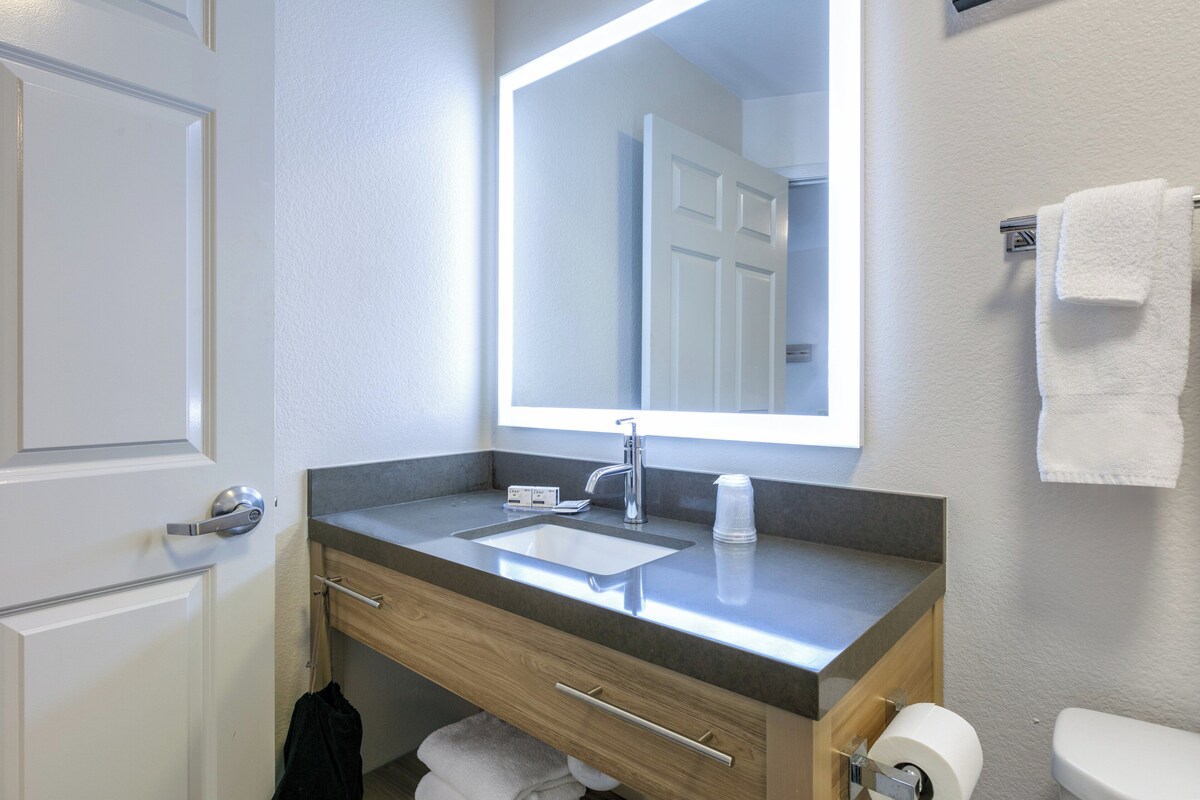 Een badkamer met een wastafel, spiegel, handdoekhouder en toilet.
