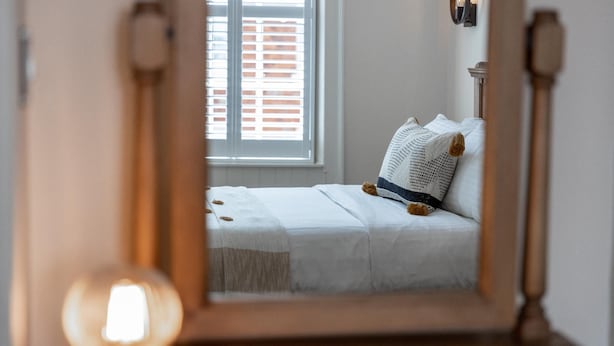 Quarto com cama, janela e espelho.