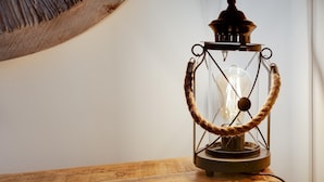 Luminária antiga em estilo retrô, com estrutura de vidro e alça de corda, sobre uma superfície de madeira.