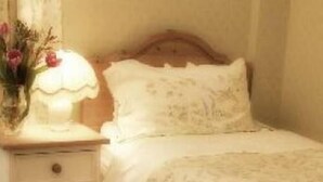 A bedroom with a wooden headboard, a bedside table with a lamp, and a floral arrangement. - Murray House (Harrogate)