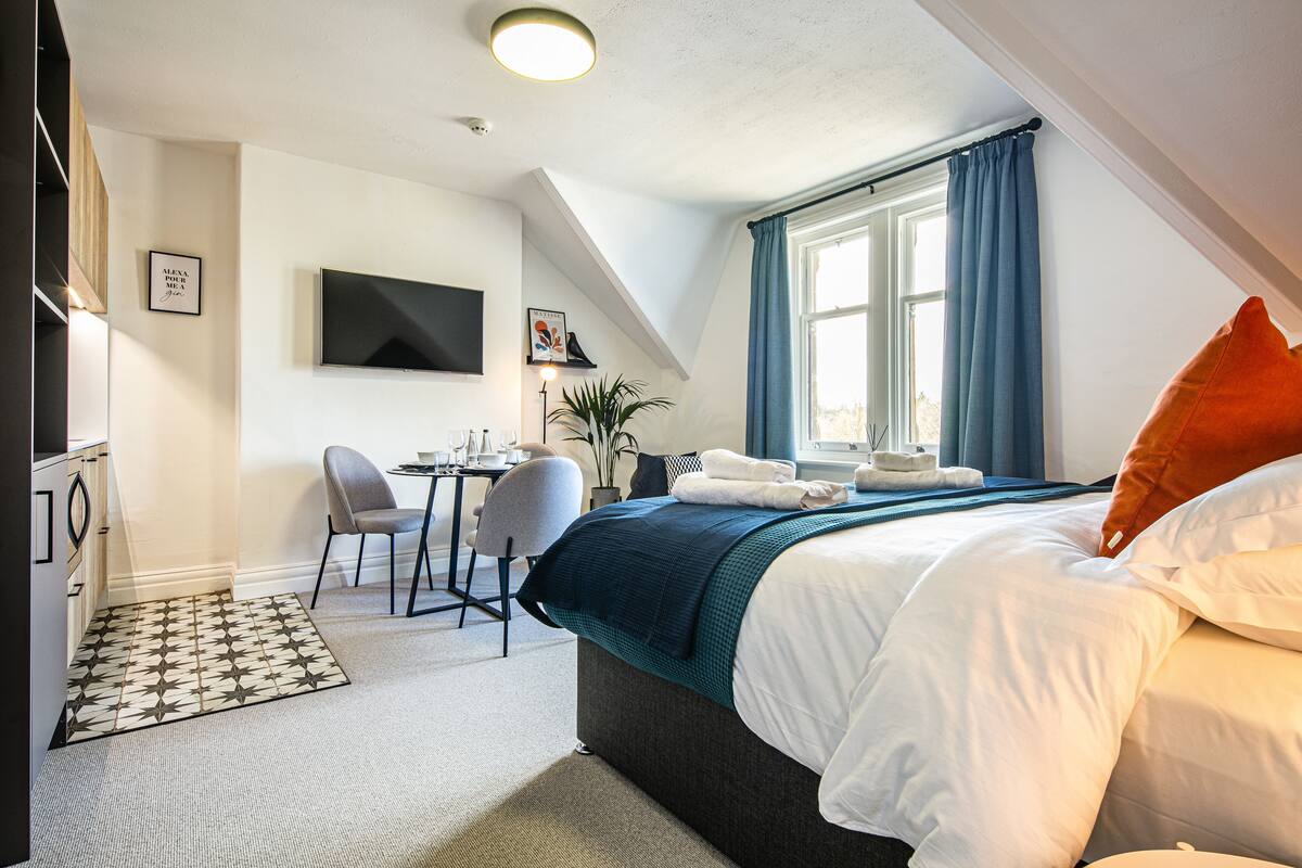 Ein Hotelzimmer mit Bett, Schreibtisch, Stuhl und Fernseher.