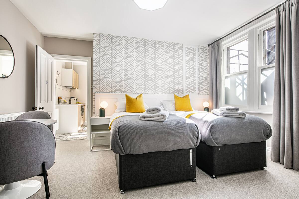 Ein modernes Hotelzimmer mit einem großen Bett, zwei Nachttischen, einem Schreibtisch und einem Sessel.