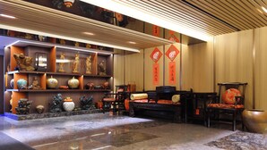 A lobby with a marble floor, wooden furniture, and shelves with decorative items. - Han She Hotel (Taipei)