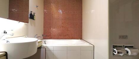 A bathroom with a white sink, a bathtub, and a toilet paper dispenser.