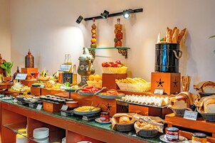 Un bufé con diversos alimentos, entre ellos frutas, verduras y pan.