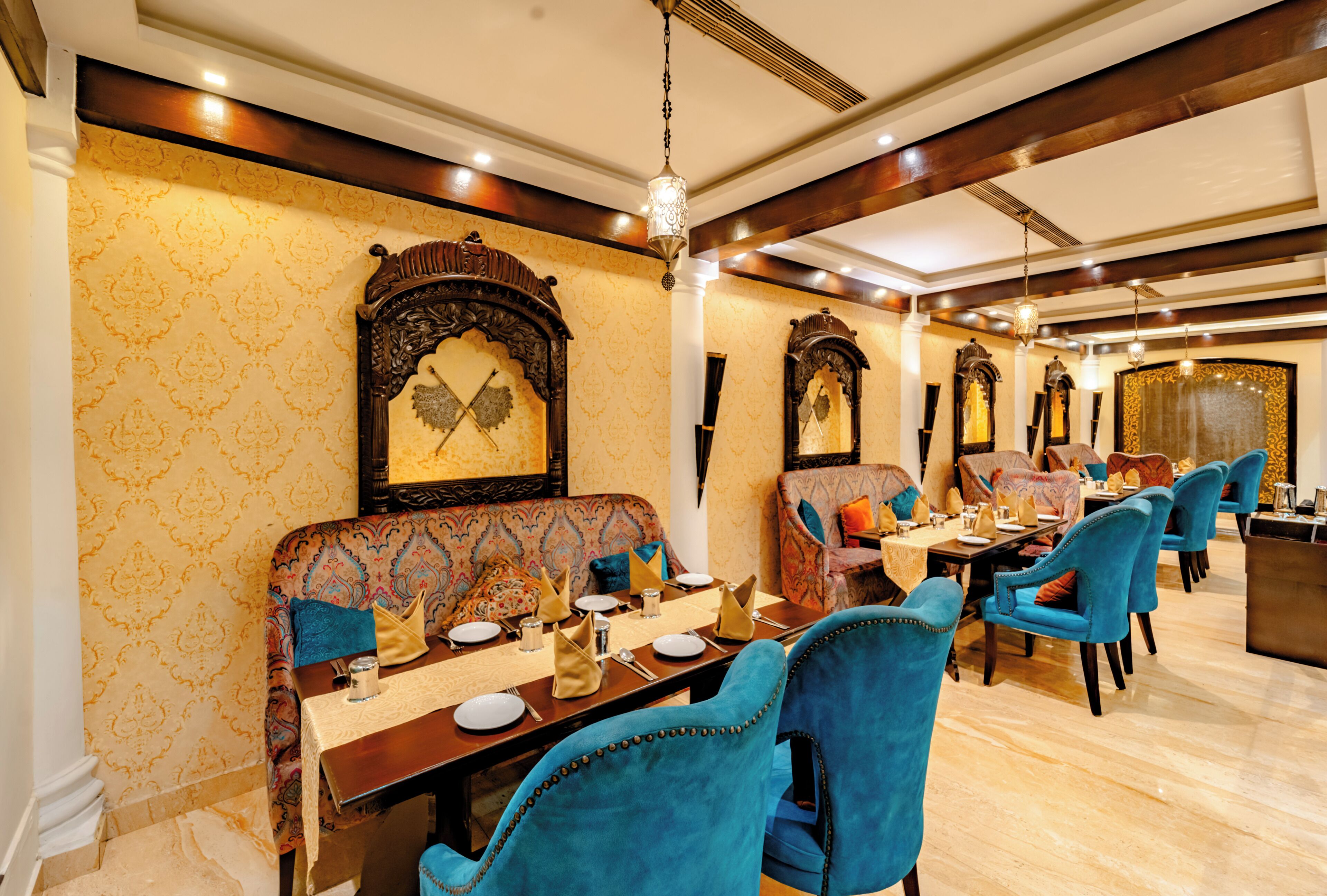 A dining area with ornate wall decorations, a chandelier, and a variety of seating arrangements.