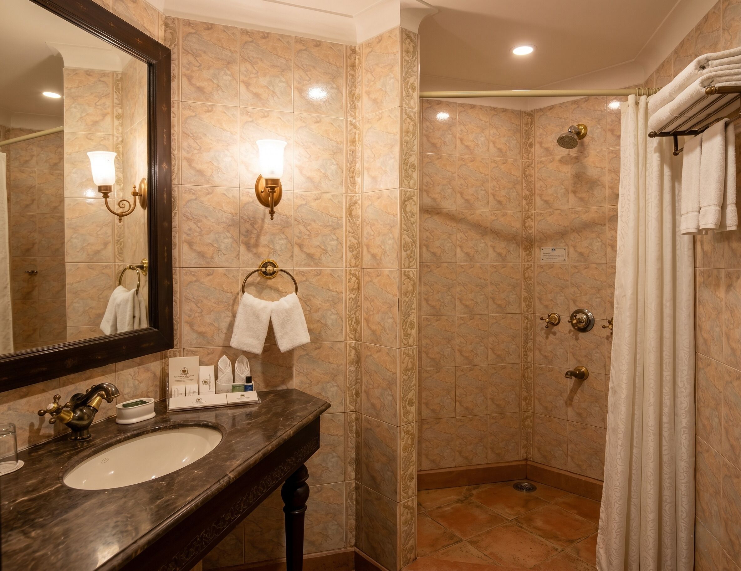 Un baño con lavabo, espejo, toallero y ducha, además de otro toallero con toallas.