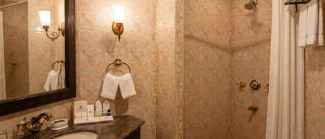 Un baño con lavabo, espejo, toallero y ducha, además de otro toallero con toallas.