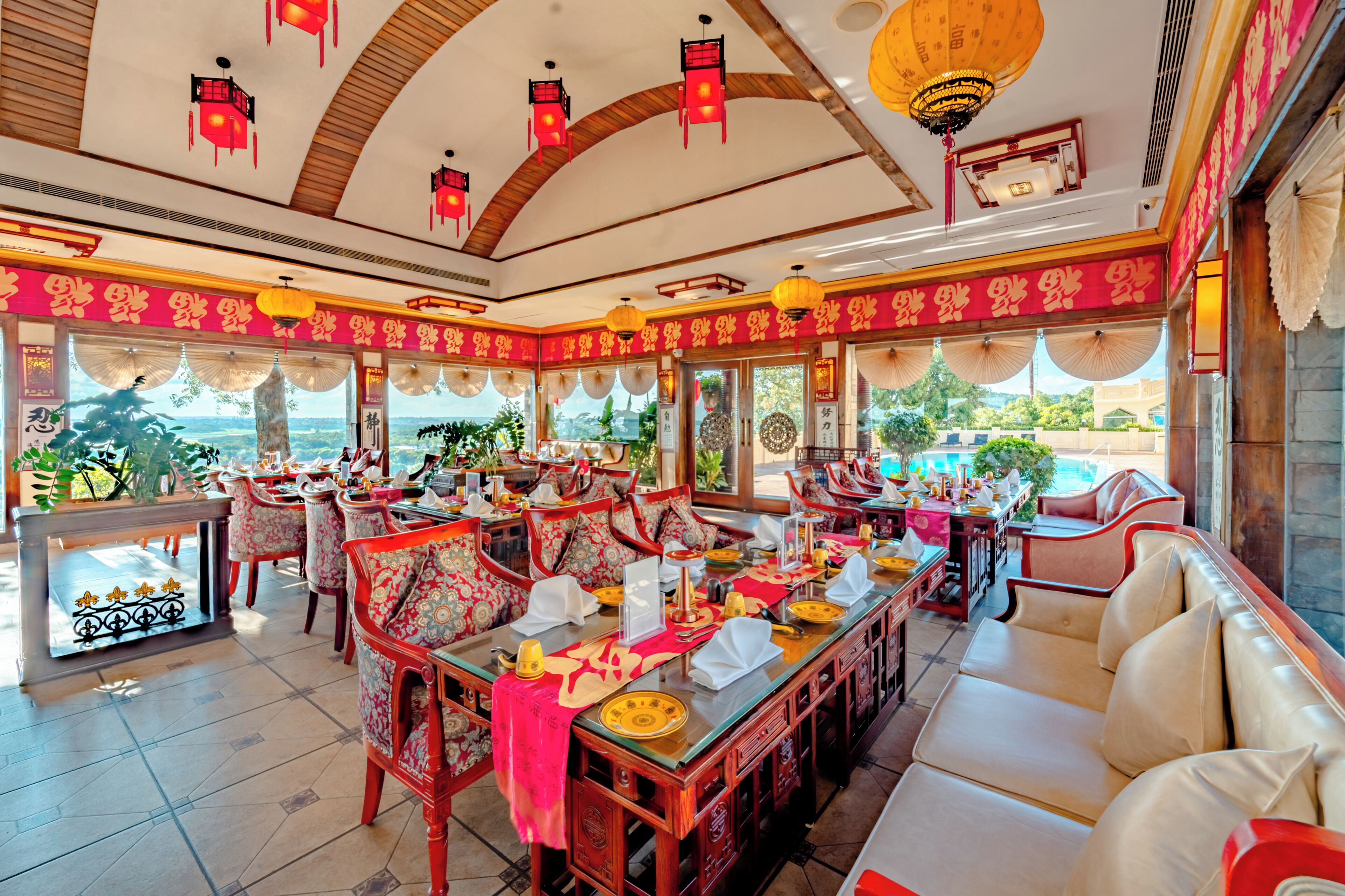 A restaurant with a long dining table, chairs, and a view of the outdoors.