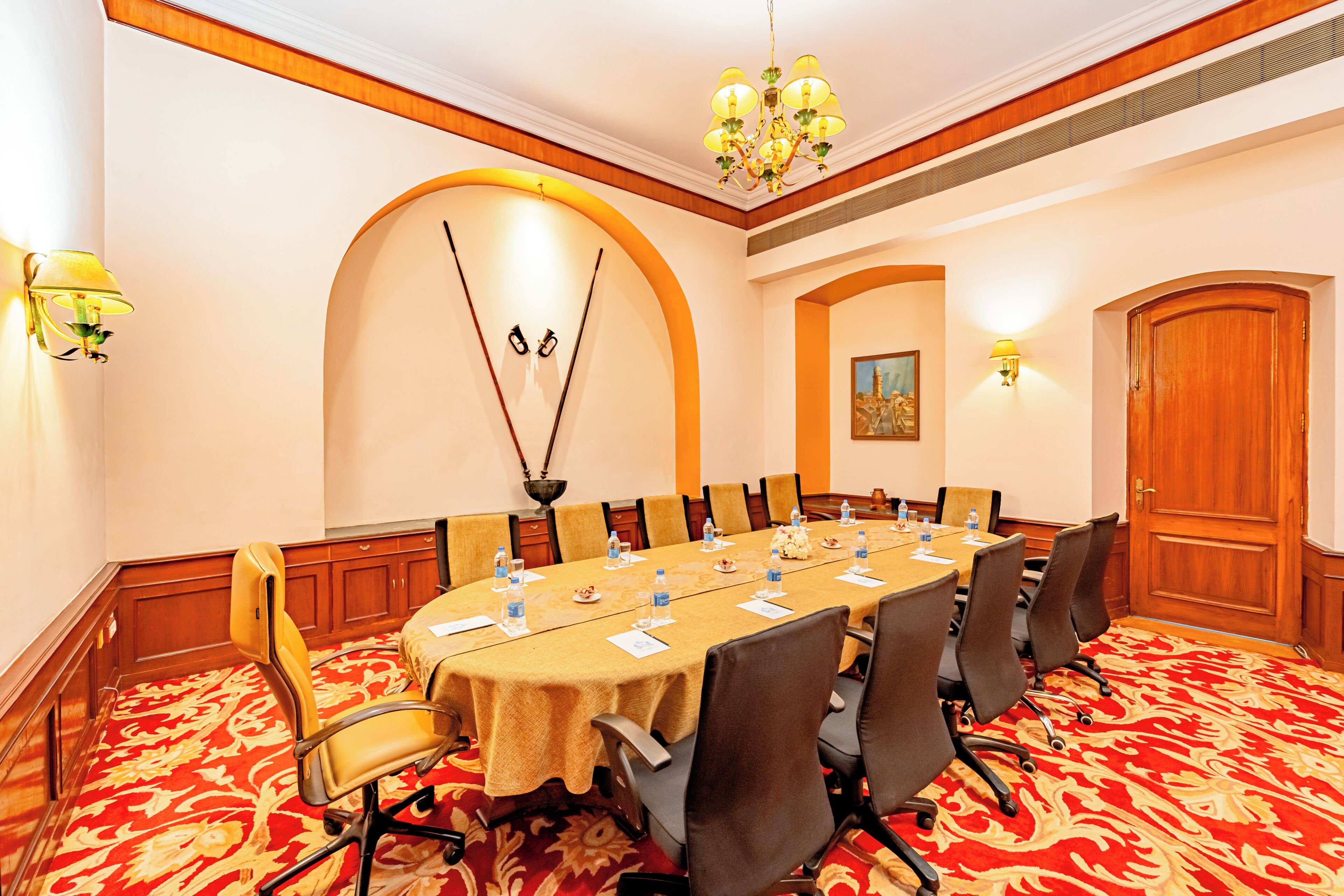 A conference room with a long table, chairs, water bottles, and a chandelier.