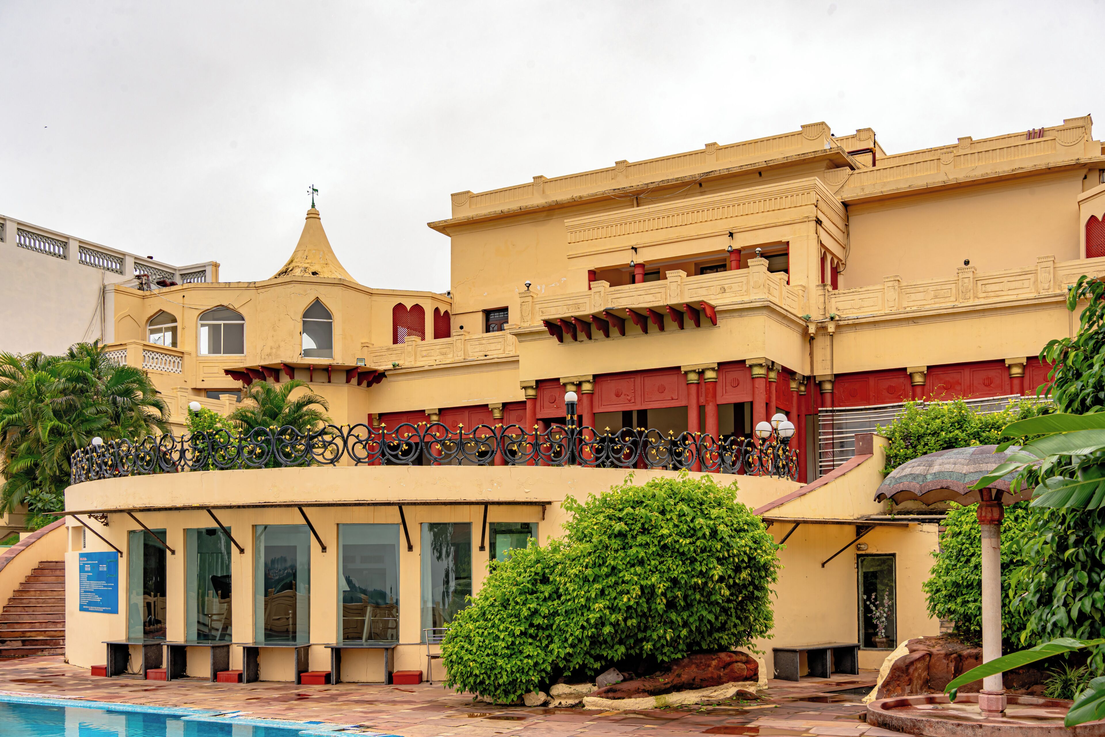 A building with a pool, a covered area with benches, and a staircase leading to the entrance.