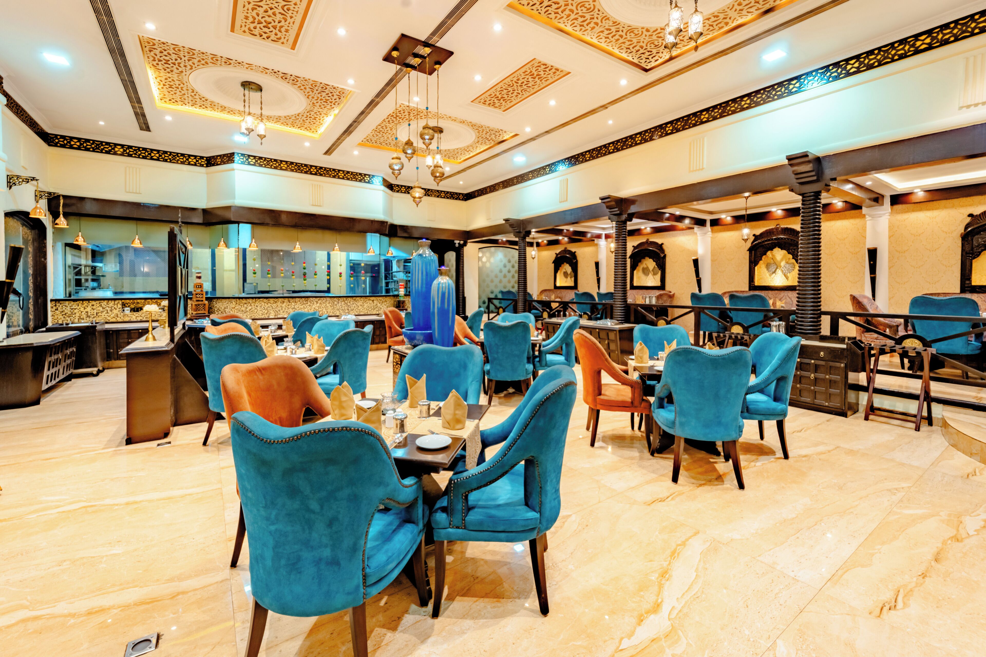 A restaurant with blue chairs, a marble floor, and ornate ceiling decorations.