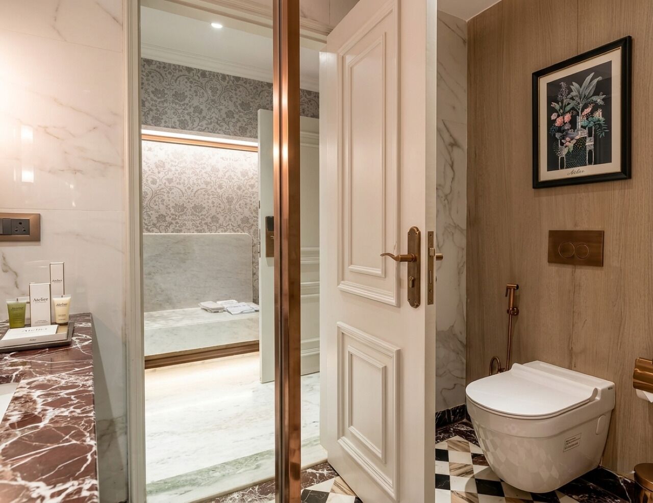 Ein Badezimmer mit Marmorboden, einer weißen Toilette, einer Duschkabine mit Glastür und einem gerahmten Pflanzenprint an der Wand.