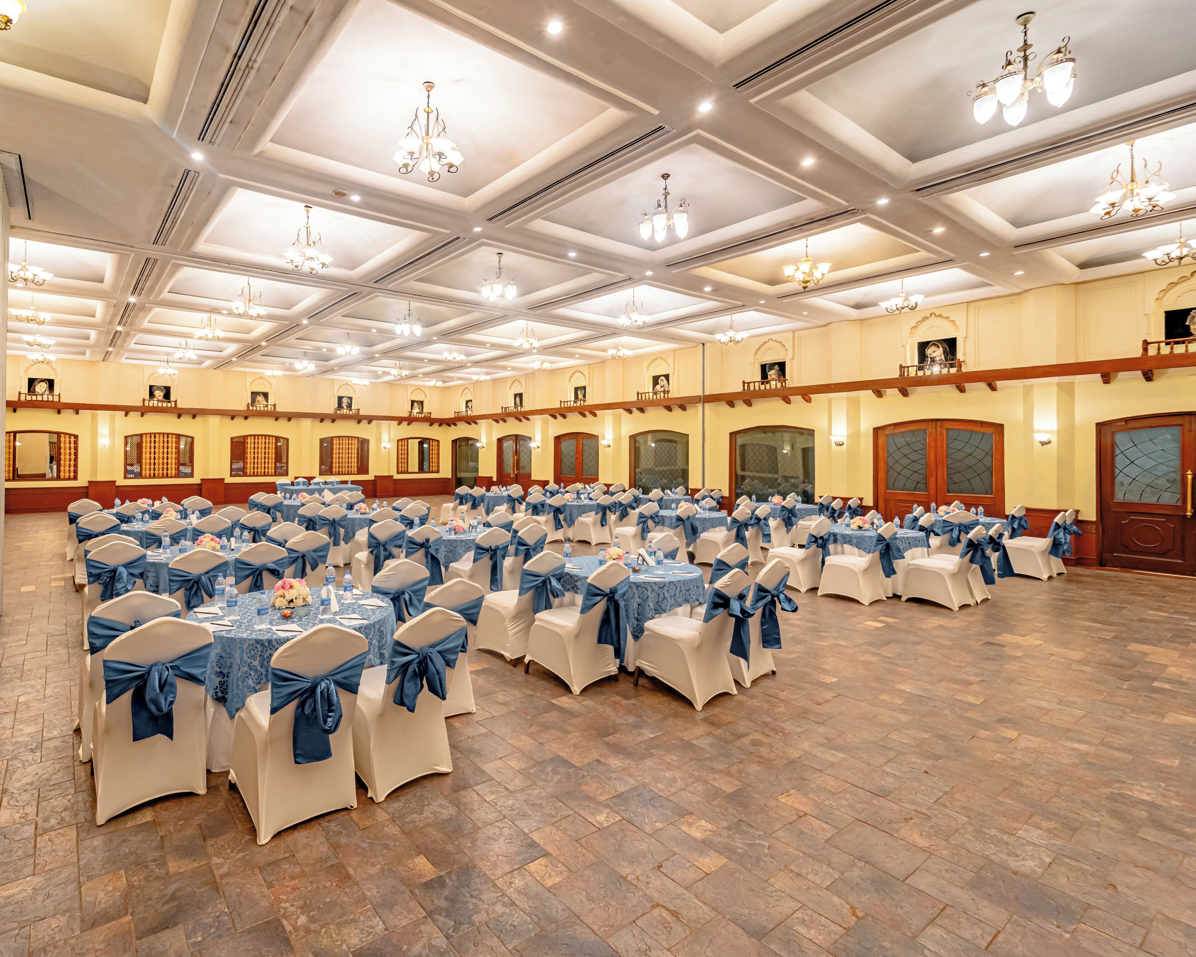 A banquet hall with rows of tables, chairs, and chandeliers.