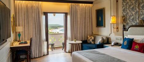 Ein Hotelzimmer mit Bett, Schreibtisch, Stuhl, kleinem Tisch und Blick ins Freie.