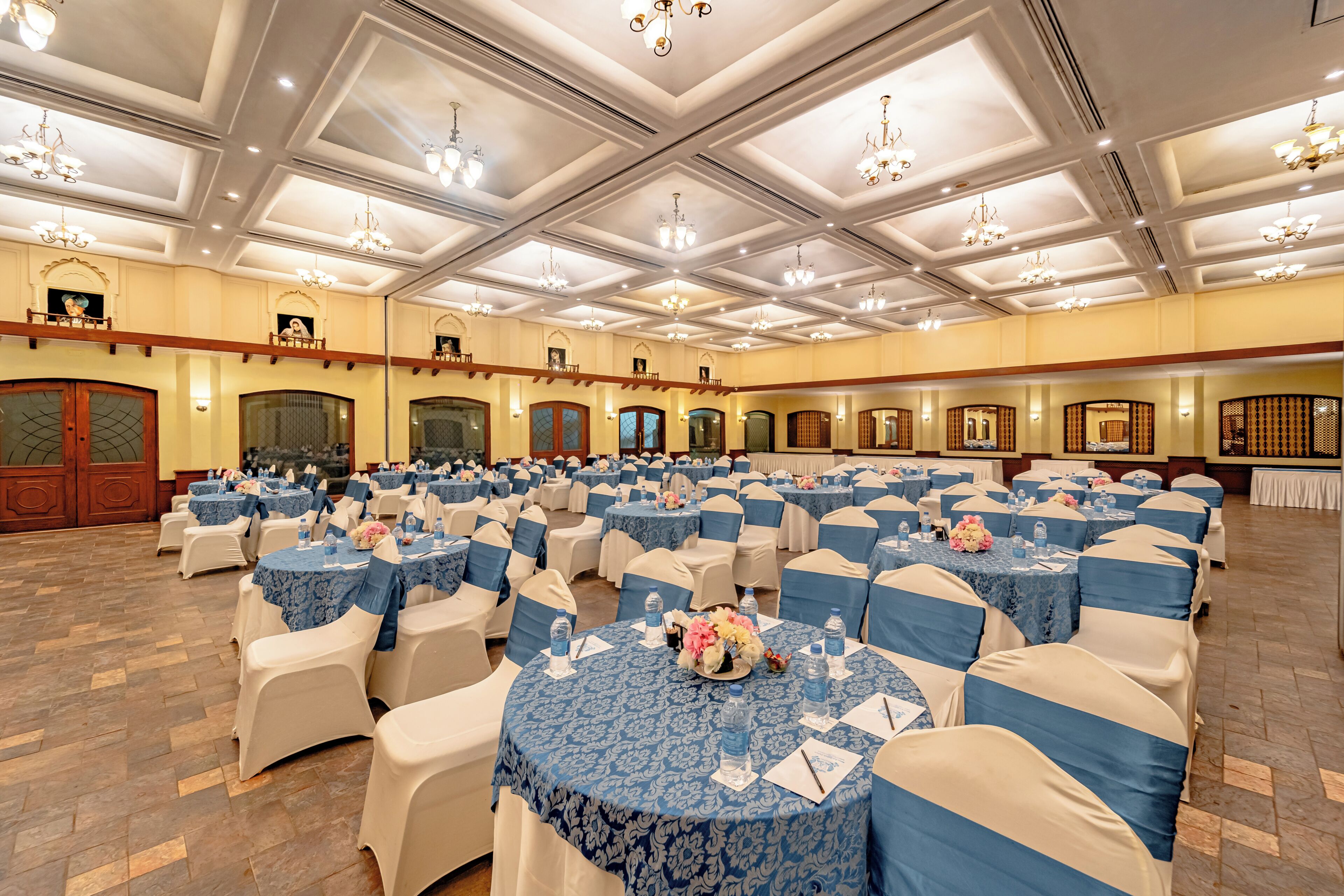 Une salle de banquet avec des tables rondes, des chaises, des lustres et un mur recouvert de miroirs.