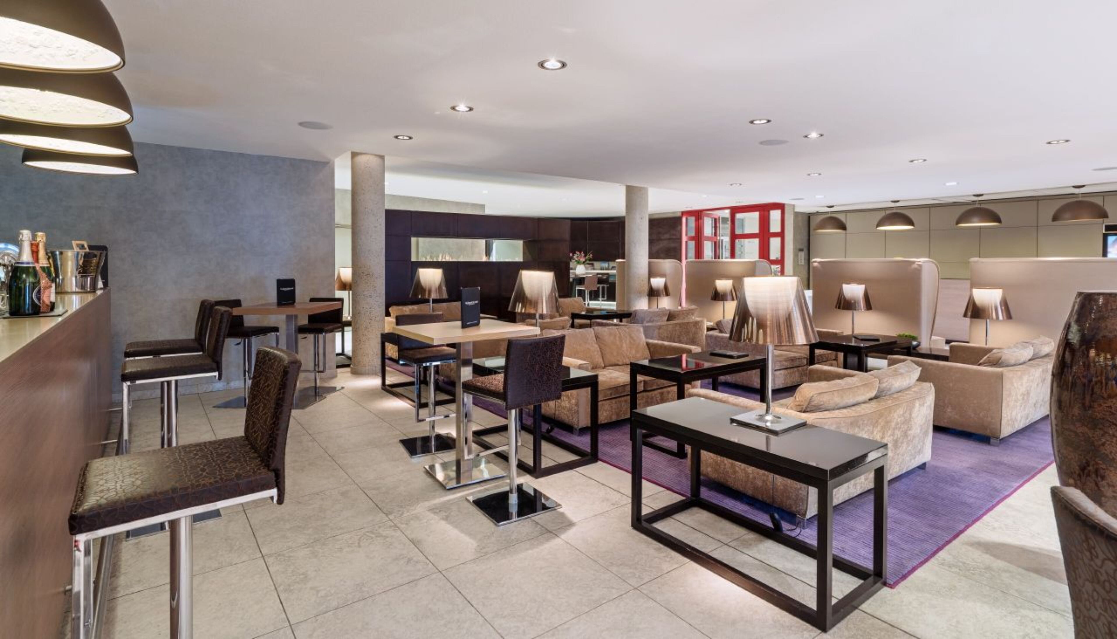 Eine moderne Hotelhalle mit Barbereich, Sitzgelegenheiten und einem sichtbaren Empfangsbereich.