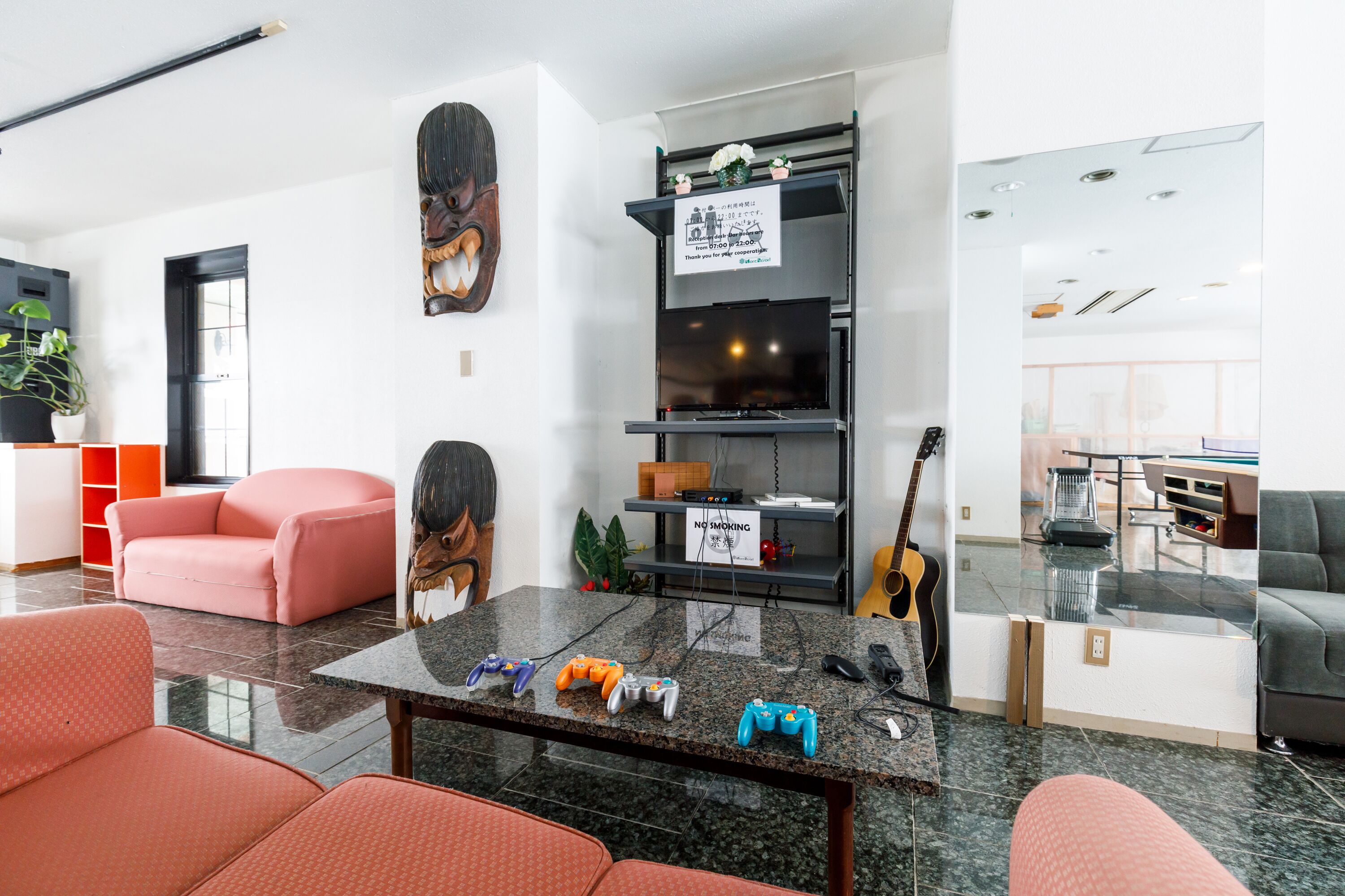 Un salon moderne avec une table basse en marbre, un canapé rose, un canapé gris et une table à manger avec un plateau en verre.