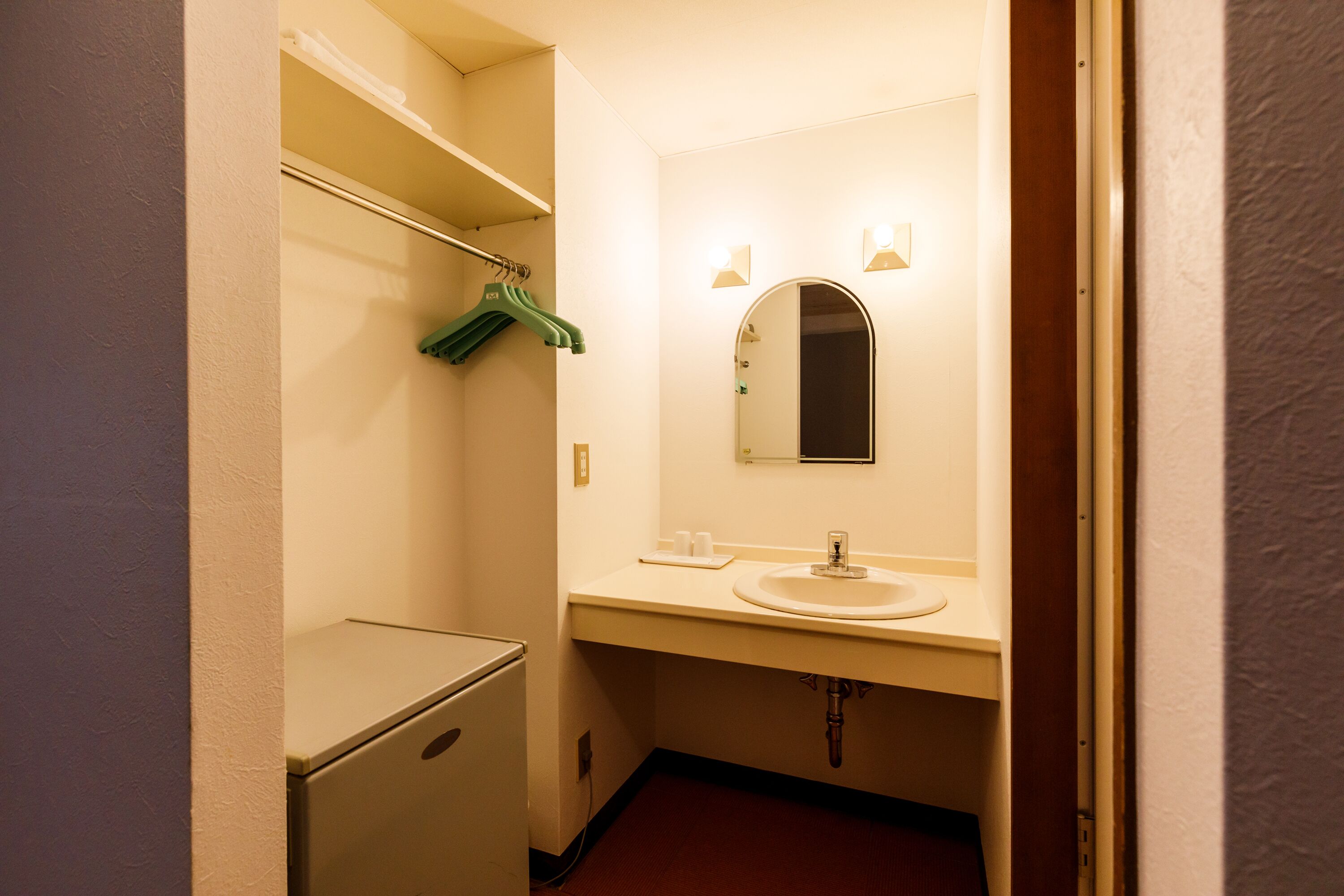A compact bathroom with a sink, mirror, and a small storage cabinet.