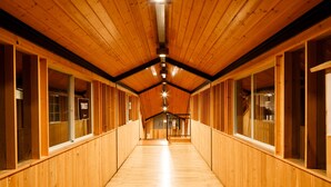 Un pasillo largo y estrecho con paredes de madera y techo inclinado.