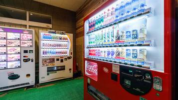 Un espace équipé de distributeurs automatiques proposant une variété de boissons, notamment du Coca-Cola et d'autres boissons.