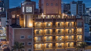 Un hotel de varios pisos con una torre de reloj, balcones y un patio.