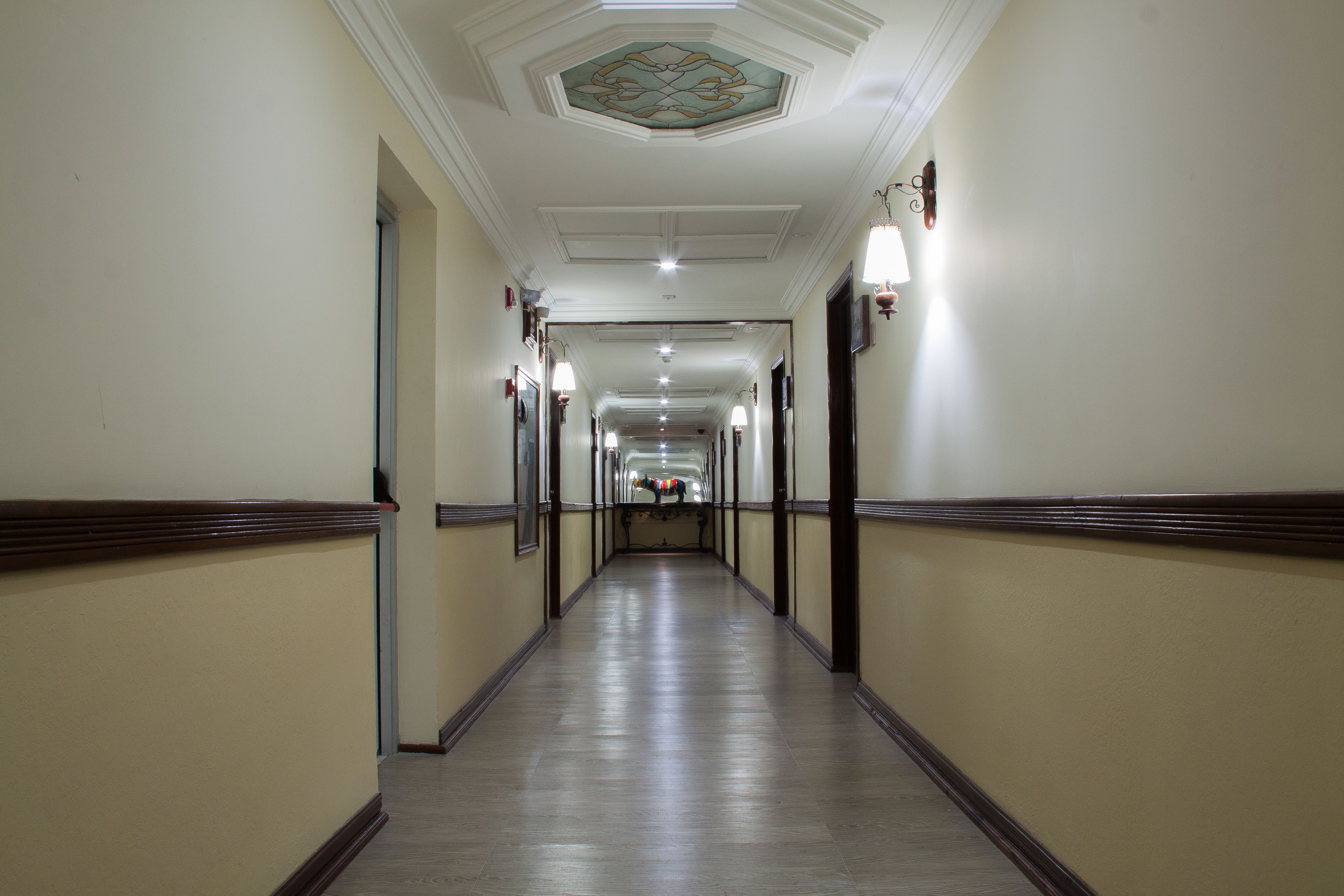 A long, narrow hallway with cream-colored walls and wooden trim, leading to a door at the end.