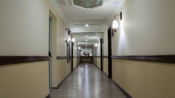 A long, narrow hallway with cream-colored walls and wooden trim, leading to a door at the end.