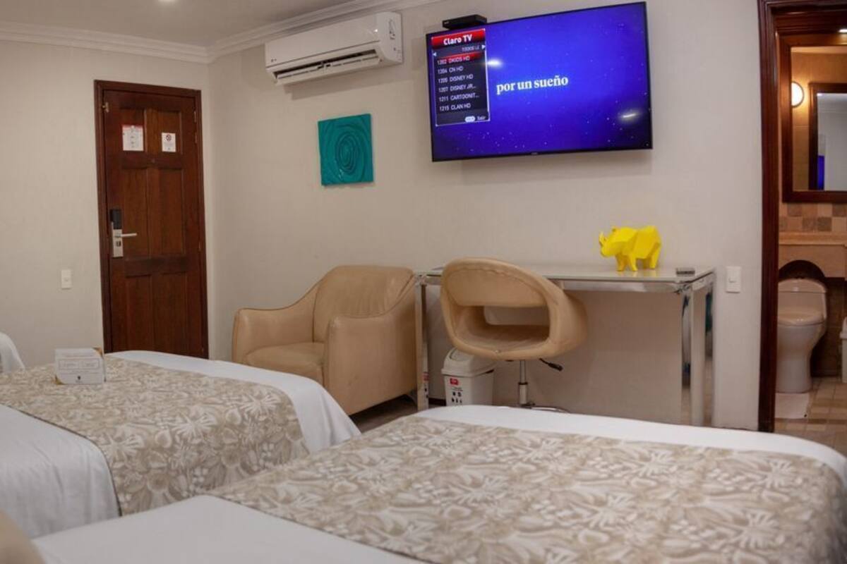 A hotel room with two beds, a TV, a desk, and a chair.