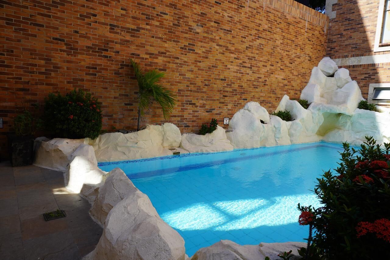 Una piscina con formaciones rocosas blancas y un muro de ladrillo al fondo.