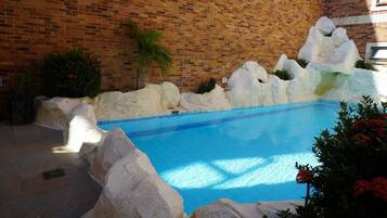Una piscina con formaciones rocosas blancas y un muro de ladrillo al fondo.