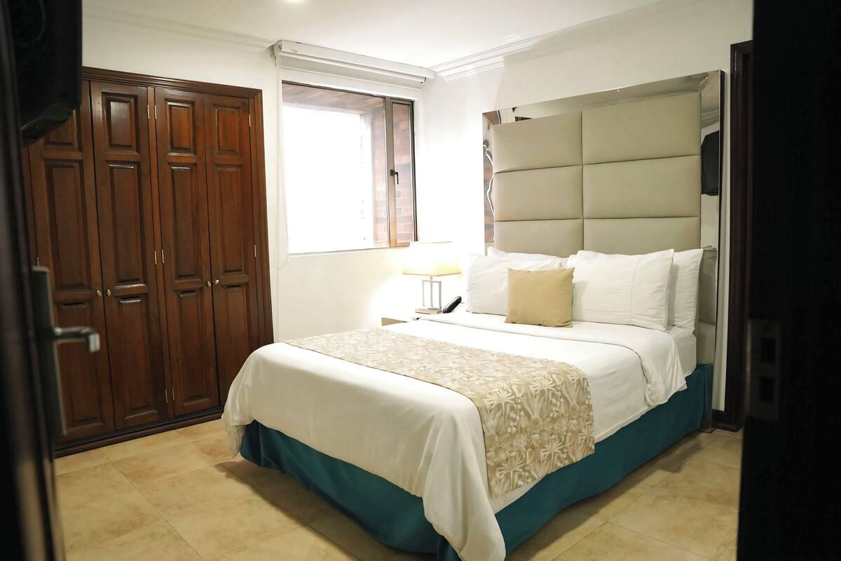 A bedroom with a bed, a wardrobe, and a window.