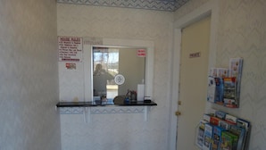 A hotel reception area with a 'No Pets Allowed' sign, a 'Private' door, and a magazine rack with various publications. - Budget Motor Inn - Mahopac (Mahopac)