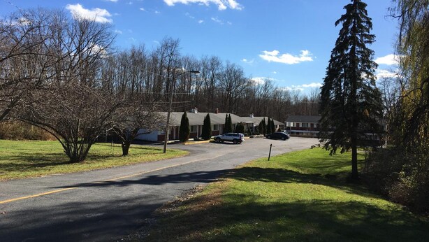 A residential street with houses, parked cars, and trees. - Budget Motor Inn - Mahopac (Mahopac)