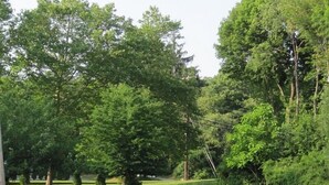 A park with mature trees, a well-maintained lawn, and a stone monument. - Budget Motor Inn - Mahopac (Mahopac)